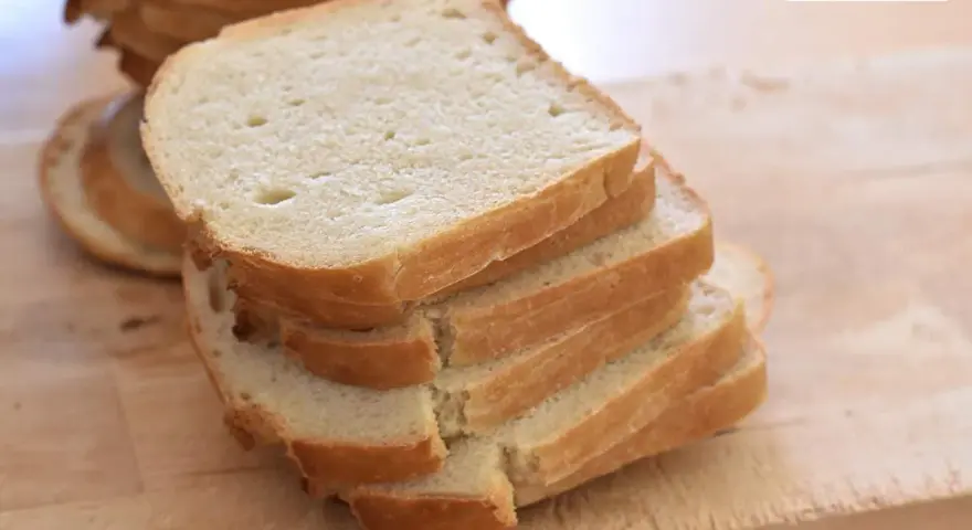 Gestapelte Scheiben eines hellen Sandwichbrots auf einem Holzbrett. Perfekt für ein einfaches Sandwich brot rezept.
