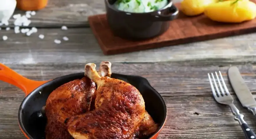 Złociste udka z airfryer w pomarańczowej patelni, obok ziemniaczki i surówka z ogórka. Pyszny obiad gotowy!