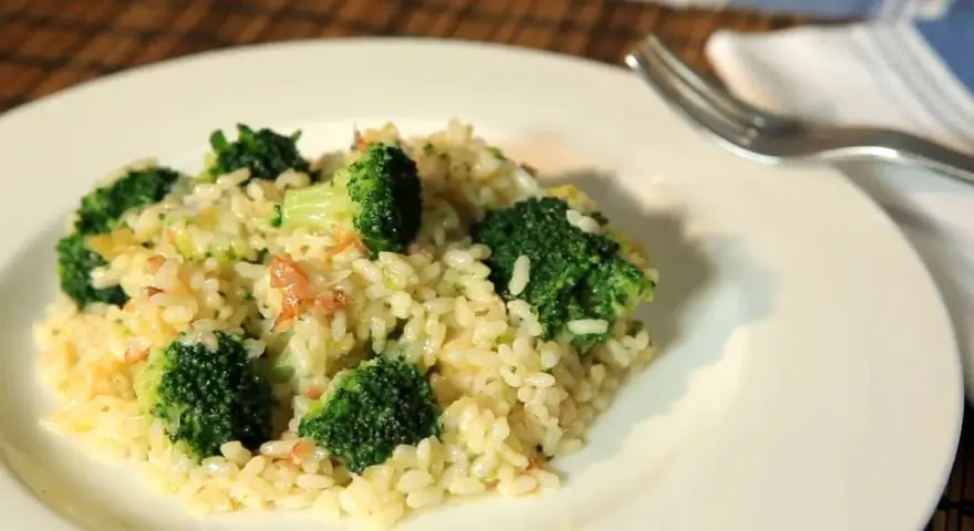 Delicioso arroz con brócoli cremoso, servido en un plato blanco con un tenedor al lado.