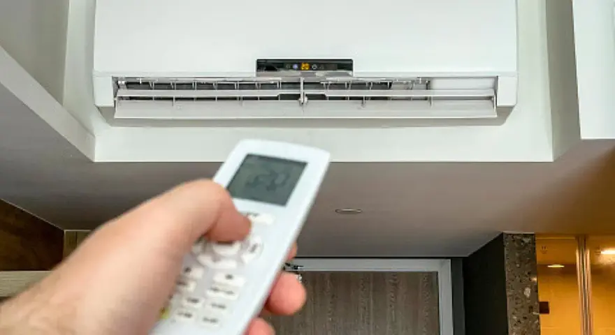 Mano ajustando el control remoto del aire acondicionado a 20 grados, ideal para saber a cuanto poner el aire acondicionado en verano y refrescar el hogar.