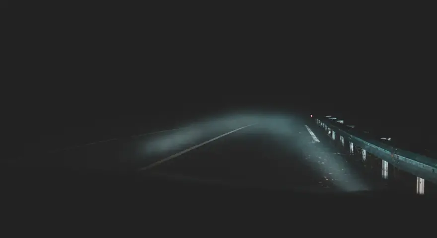 Strada buia e nebbiosa, un'atmosfera che evoca la differenza tra giallo e thriller. I fari illuminano un percorso incerto.