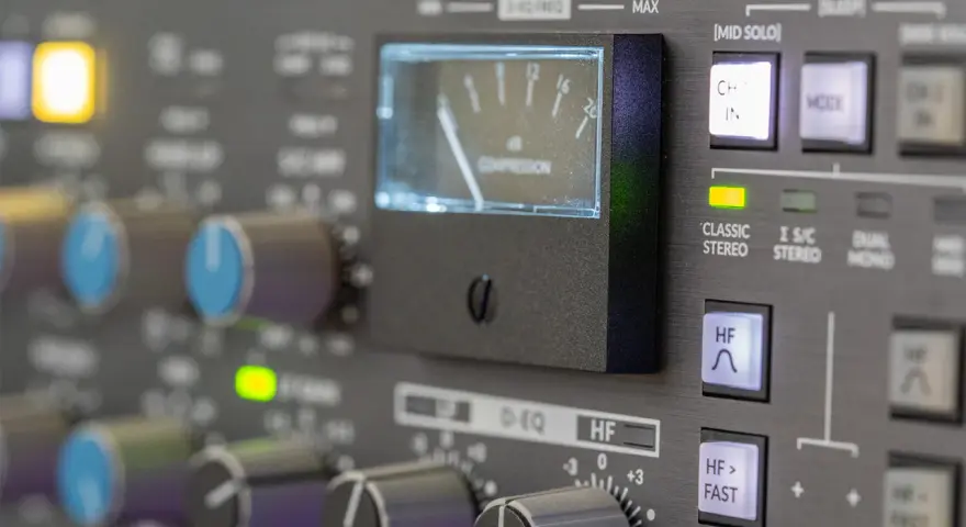 Regler und VU-Meter eines Mischpults, das die analoge Welt der Musikproduktion zeigt.