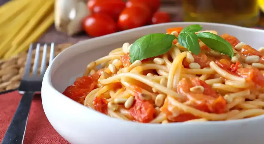 Spaghetti con pomodorini, pinoli e basilico, un'idea per sughi estivi per pasta freschi e veloci.