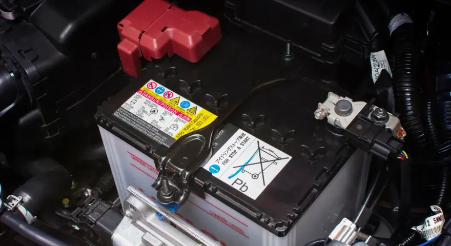 Autobatterie im Motorraum, mit Warnhinweisen. Die Batterie ist tiefentladen und muss ersetzt werden.
