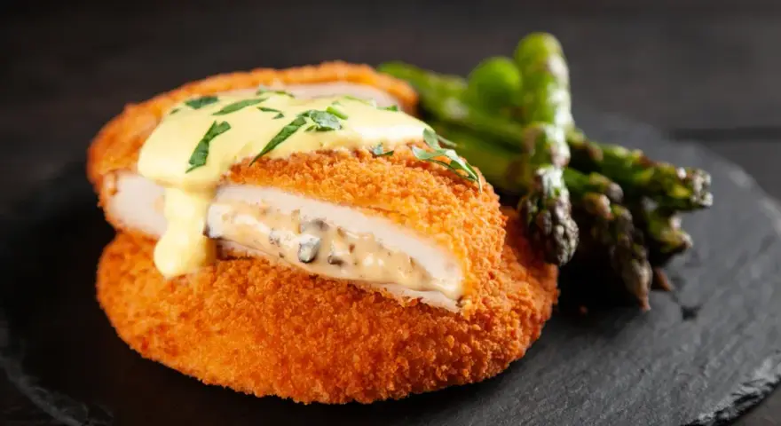 Krispig cordon bleu med krämig fyllning och hollandaisesås, serverad med sparris.