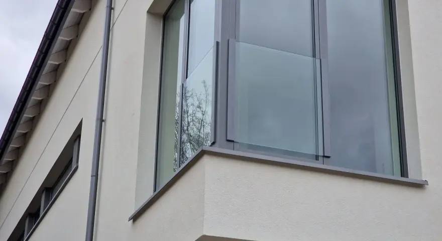 Nowoczesne portfenetry z przeszklonymi balustradami na jasnej elewacji.