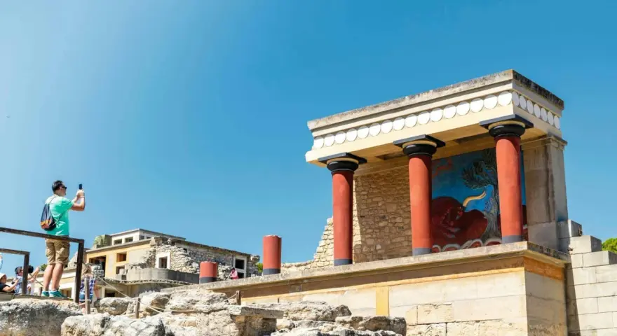 Zwiedzający robi zdjęcie fresku z bykiem w starożytnym pałacu w Knossos.