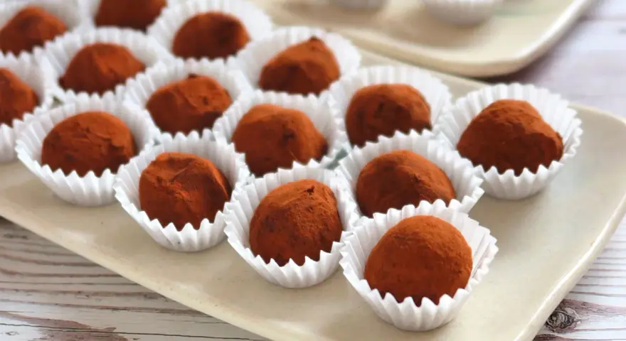 Deliciosas trufas de chocolate cubiertas de cacao, presentadas en sus envoltorios blancos.
