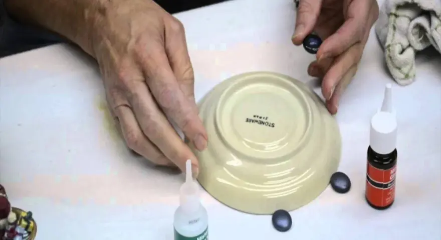 Mani che lavorano per riparare la ceramica con colla e piccoli pezzi.