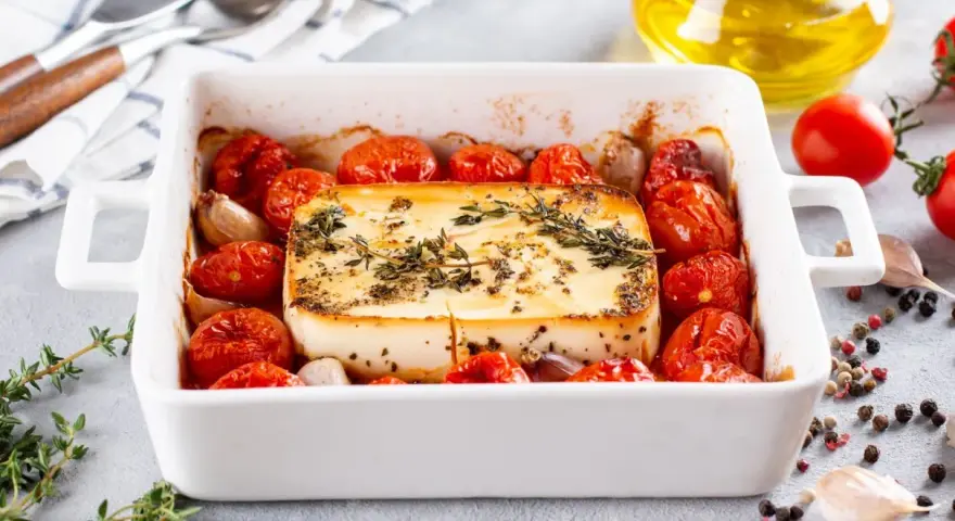 Pieczeni ser feta z pomidorkami koktajlowymi i czosnkiem, idealne dania na imprezę na ciepło.