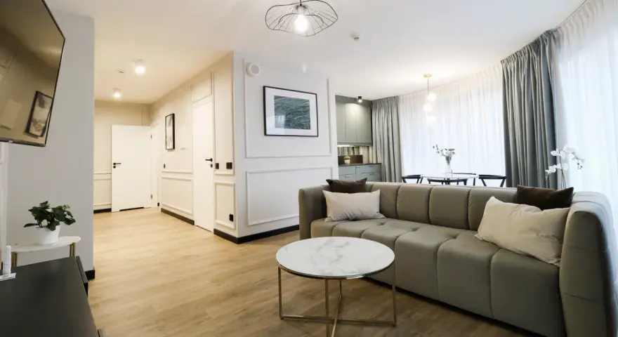 Nowoczesny apartament suite, z wygodną kanapą, stolikiem kawowym i widokiem na kuchnię.