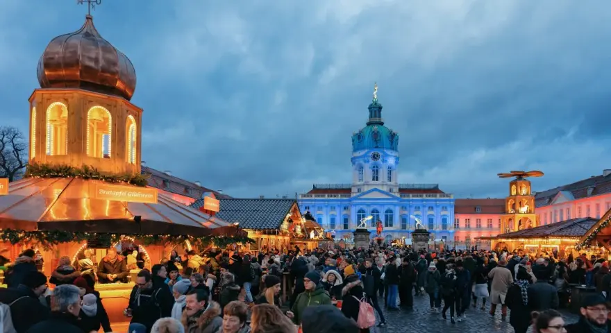 Besucher genießen den Weihnachtsmarkt vor dem beleuchteten Schloss Charlottenburg in Berlin.
