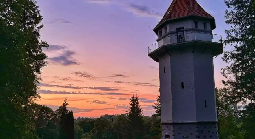 Wieża widokowa w Rynie, jedna z lokalnych atrakcji, na tle zachodzącego słońca.