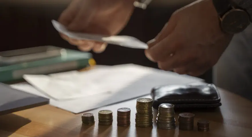 Ręce liczą pieniądze nad stosem monet, symbolizującym trudną sytuację finansową i potencjalną upadłość przedsiębiorcy.