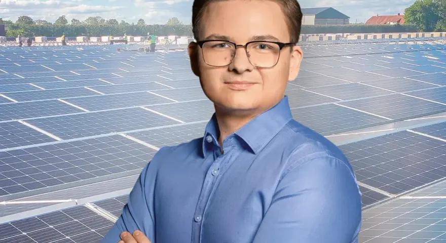 Mężczyzna w okularach na tle farmy fotowoltaicznej. Szanuj energię, nie daj się oszustom.
