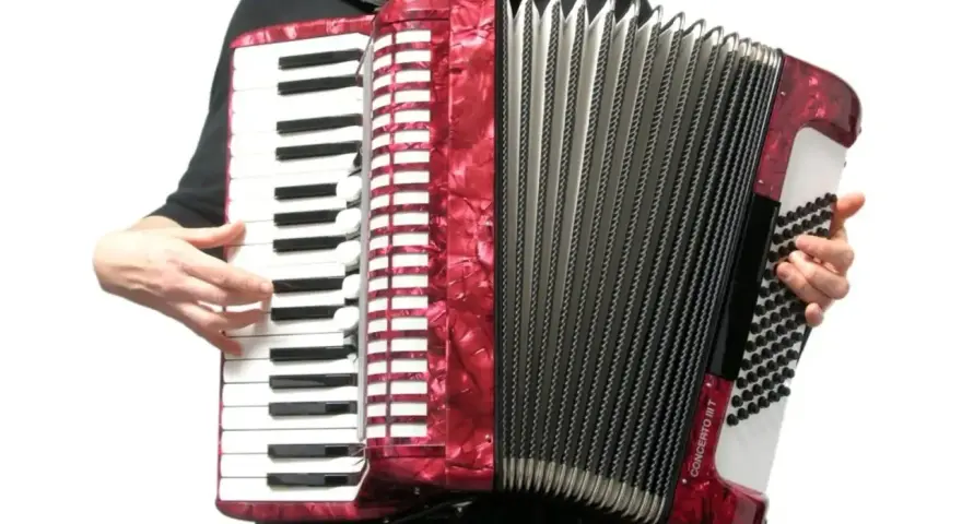 Ręce grają na czerwonym akordeonie, wydobywając dźwięki tego wspaniałego instrumentu.