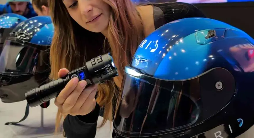 Donna mostra un casco da moto blu con visiera, evidenziando la sua importanza per la sicurezza. È bene che il casco sia dotato di visiera.