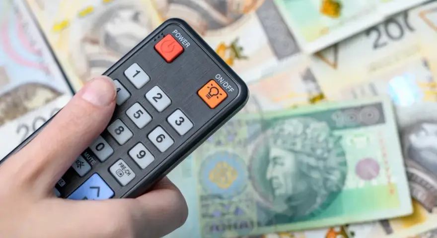 Pilot w dłoni, na tle polskich banknotów. Czy to symbol zwolnienia z abonamentu RTV i oszczędności?