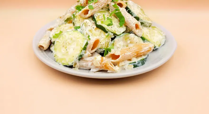 Makaron z cukinii przepis: penne w kremowym sosie z plasterkami cukinii, posypane natką pietruszki i pieprzem.