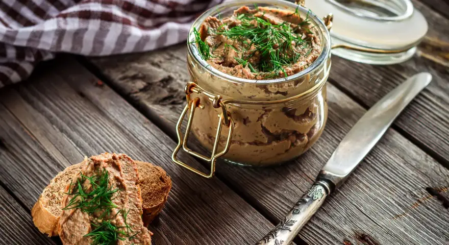 Un tarro de rillettes, paté de cerdo desmenuzado, con eneldo fresco, servido sobre pan tostado.