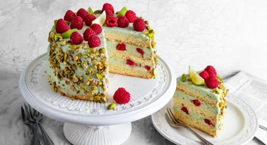 Wyjątkowy tort pistacjowy z malinami i limonką, ozdobiony chrupiącymi pistacjami. Idealny na każdą okazję.