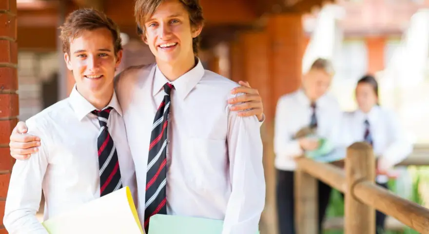 Deux adolescents souriants, portant des chemises blanches et des cravates, profitent de leurs vacances scolaires en Irlande.