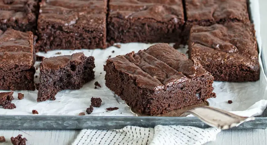 Saftige Schokoladen-Brownies, perfekt für jedes Brownie Rezept. Ein Stück wird gerade herausgehoben.