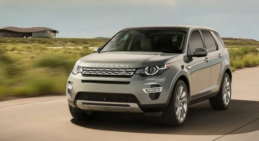 Szary Land Rover Discovery Sport w ruchu, z widocznym napisem "DISCOVERY". Czyżby kolejne awarie?