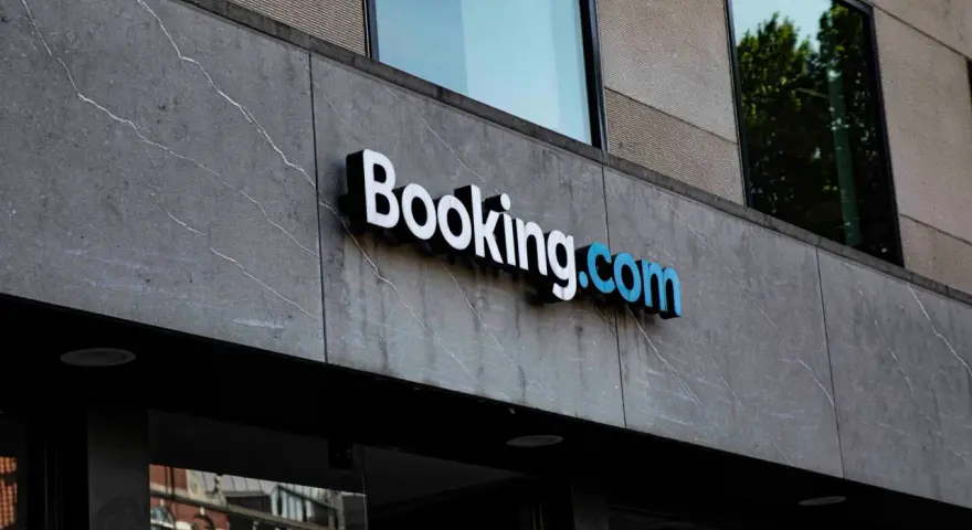 Logo Booking.com na szarym, kamiennym budynku. Planujesz podróż i szukasz najlepszych ofert? Z booking cashback Twoje wakacje będą tańsze!