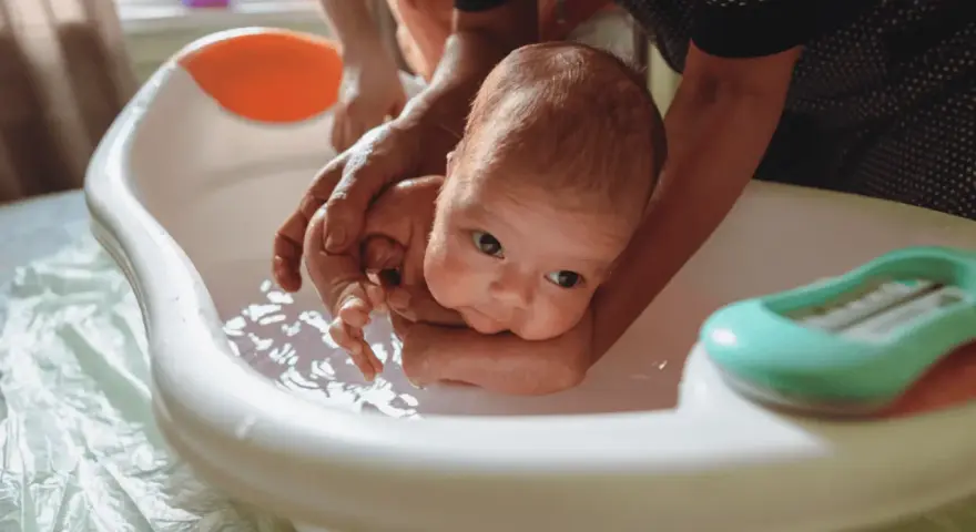 Delikatne kąpiel noworodka w wanience. Czy przy gorączce można kąpać dziecko? Tak, ale w letniej wodzie.