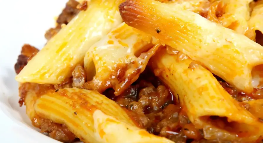 Macarrones con carne y queso fundido, cubiertos con salsa de tomate.