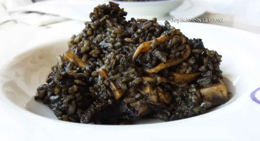 Un plato de arroz negro con trozos de calamar, servido en un cuenco blanco.