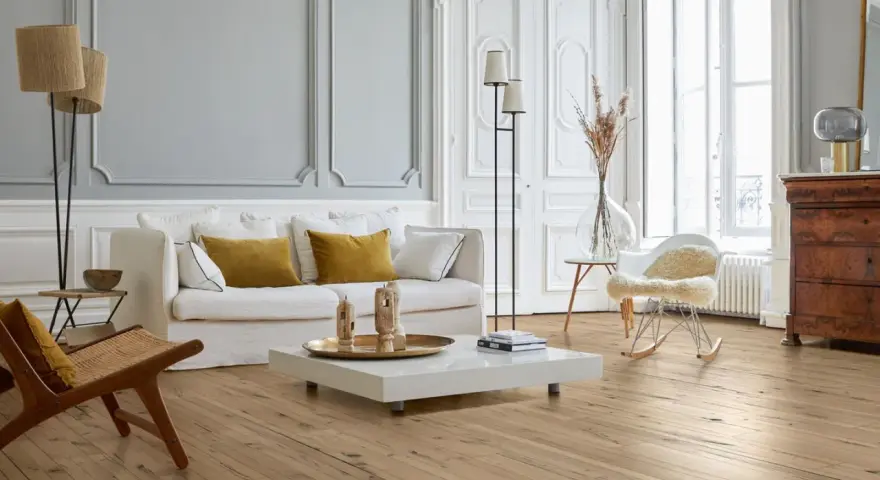 Stilvolles Wohnzimmer mit hellem Parkettboden, der durch regelmäßige Parkett Pflege glänzt. Gemütliche Couch, Sessel und ein moderner Couchtisch.