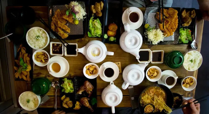 Mesa llena de platos asiáticos, teteras y tazas. Una experiencia culinaria en un restaurante sensorial.