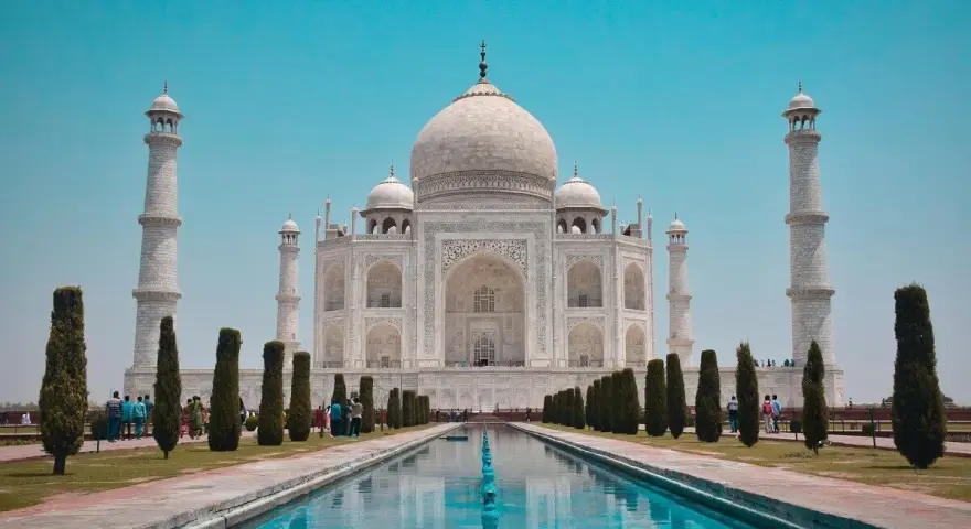 El Taj Mahal, en Agra, India, se alza majestuoso con su cúpula blanca y minaretes, reflejado en el estanque.