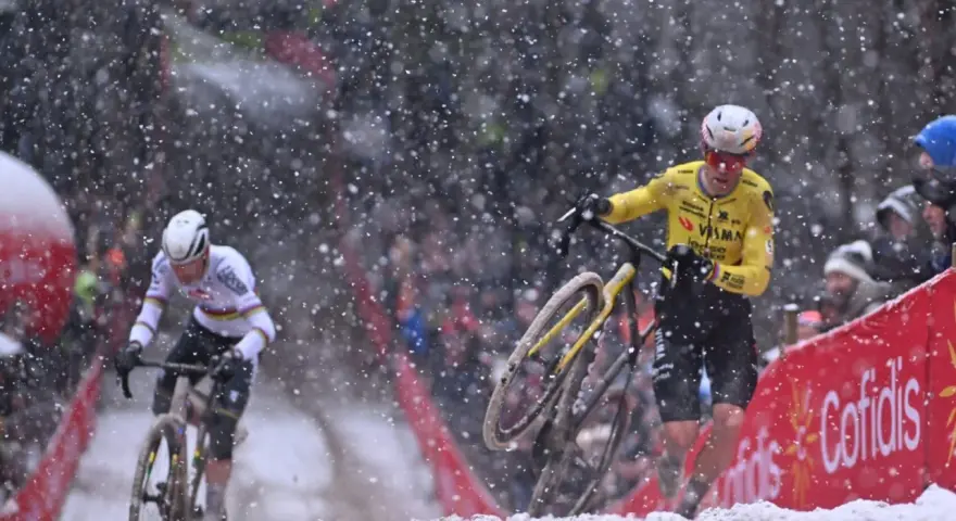 Cyclists battle snowy conditions. Wout van Aert, in yellow, appears to be recovering from a crash, while another rider in white pushes on.