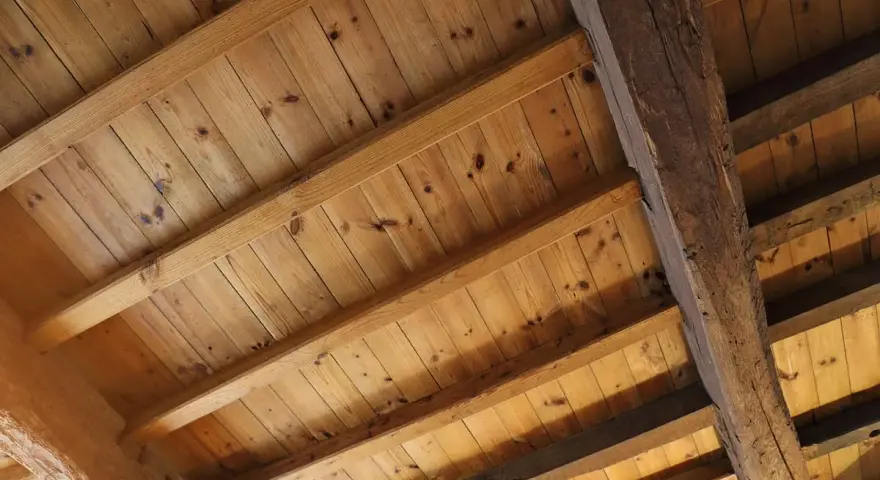 Holzbalkendecke sanieren: Alte Holzbalken und Holzbretter bilden eine rustikale Decke, die bereit für eine Sanierung ist.