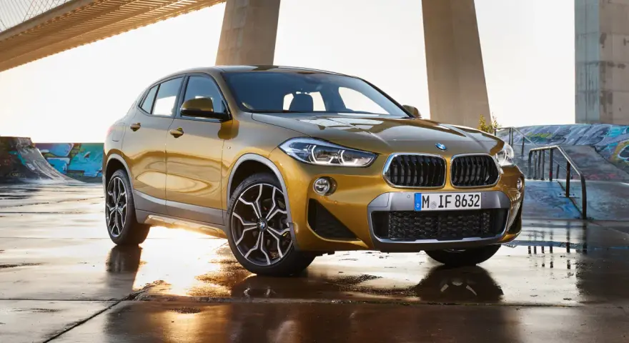 Złoty BMW X2 na tle mostu i skateparku. Nowoczesny leasing jak abonament, bez zobowiązań.