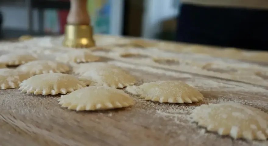 Ravioli co to? Świeżo przygotowane pierożki z ciasta makaronowego, posypane mąką, czekają na gotowanie.