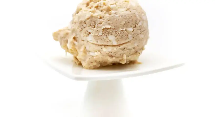 Eine Kugel Milchreis Eis auf einem weißen Teller. Cremig und mit Stückchen, ein Genuss!