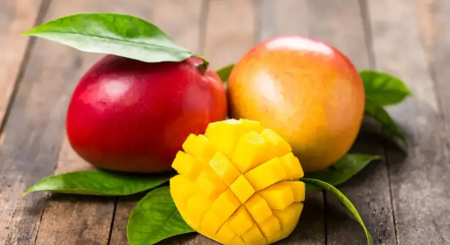 Dwa soczyste mango, jedno czerwone, drugie pomarańczowe, i jedno pokrojone w kostkę, idealne, gdy jest sezon na mango.