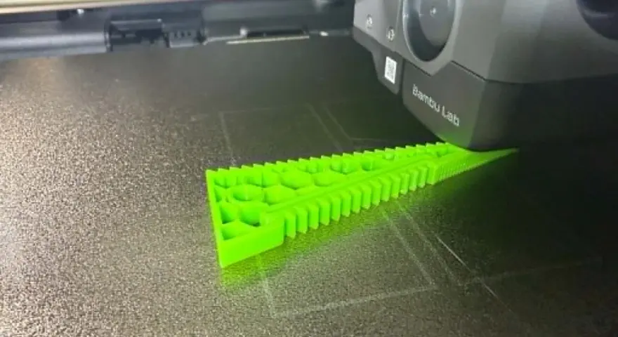 Drukarka 3D tworzy zielony obiekt z filamentu TPU, pokazując jego elastyczne właściwości.