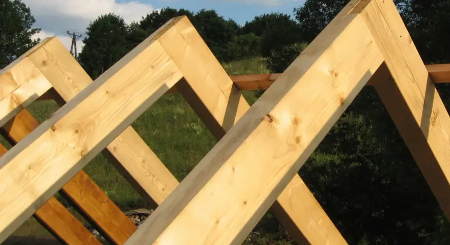 Drewniane krokwie tworzą konstrukcję dachu, ich łączenie w szczycie jest solidne i gotowe na kolejne etapy budowy.
