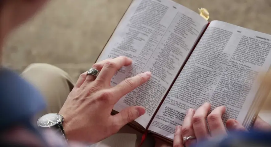 Dłonie pary przeglądają Biblię, szukając pocieszenia i siły przeciwko złemu duchowi.