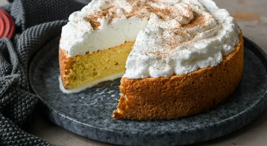 Tarta tres leches esponjosa, cubierta de merengue y espolvoreada con canela. Se ve deliciosa y lista para disfrutar.
