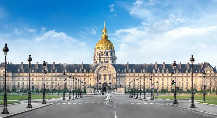 Imponente cúpula dorada del Hôtel des Invalides en París, con su fachada clásica y farolas a ambos lados de la avenida.