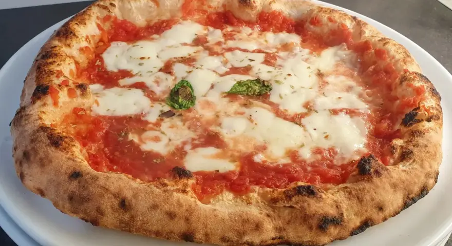 Pizza a lunga lievitazione con pomodoro, mozzarella filante e basilico fresco. Croccante fuori, soffice dentro, un vero capolavoro.