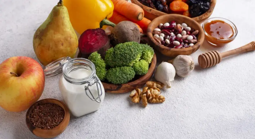 Składniki na zdrową dietę jelitową: jabłko, gruszka, brokuły, buraki, marchew, papryka, fasola, orzechy, czosnek, siemię lniane, jogurt, suszone owoce i miód.