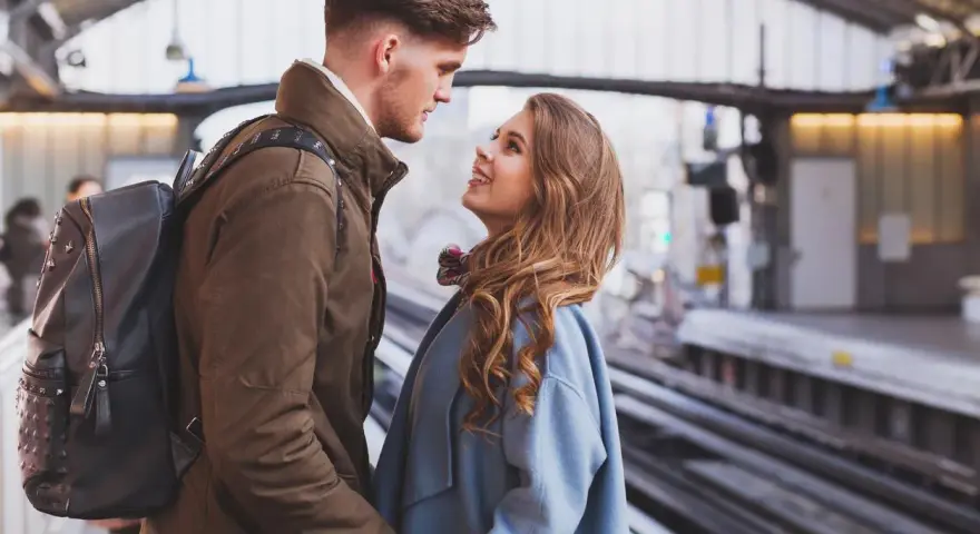 Un couple se regarde avec tendresse sur un quai de gare, un moment où l'on peut se sentir connecté à quelqu'un à distance.