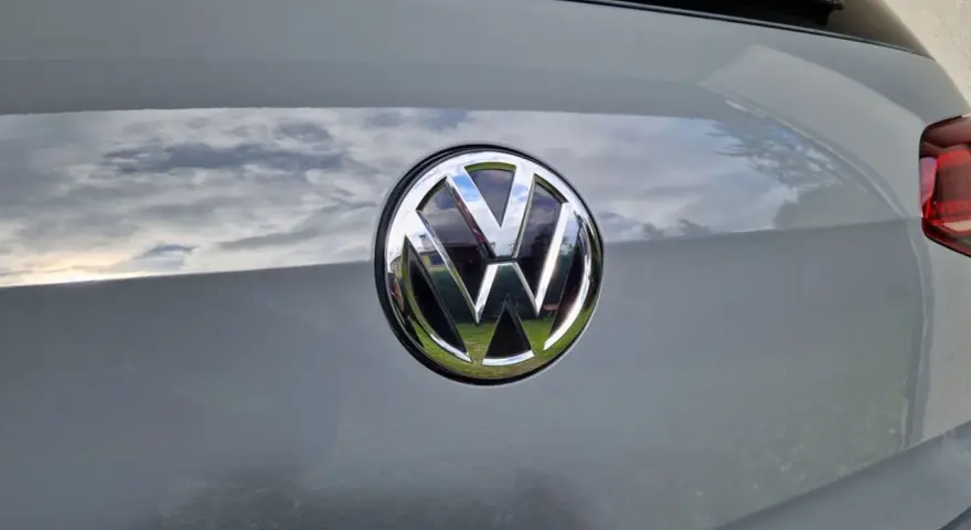 Das VW-Logo auf dem Heck eines grauen Autos. Eine Erklärung zum Fahrzeugdatenträger VW ist hier nicht ersichtlich.